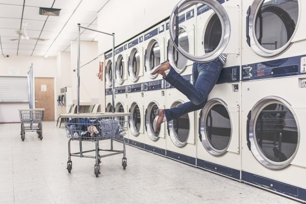 person dives into laundromat dryer